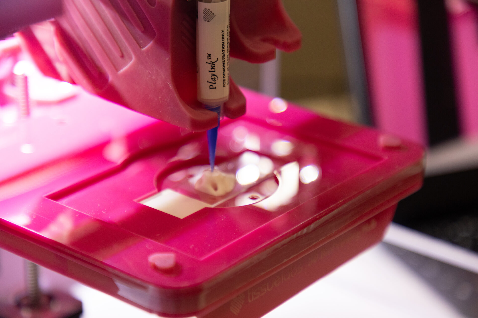 Bioimpressora 3D depositando biotinta rosada sobre uma placa de cultivo durante o lançamento do Hub de Bioimpressão 3D da Merck com a Coppe/UFRJ